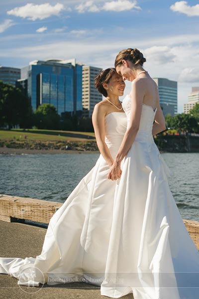 brides holding hands by the water