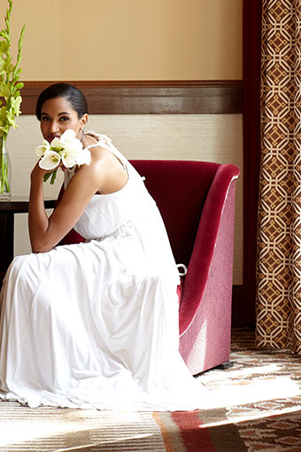 Bride sits on chair holding a single flower at Kimpton Riverplace Hotel