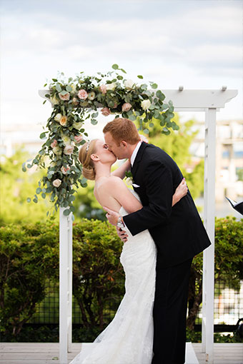 Bride and groom kiss in front of ceremony decor at Kimpton Riverplace Hotel